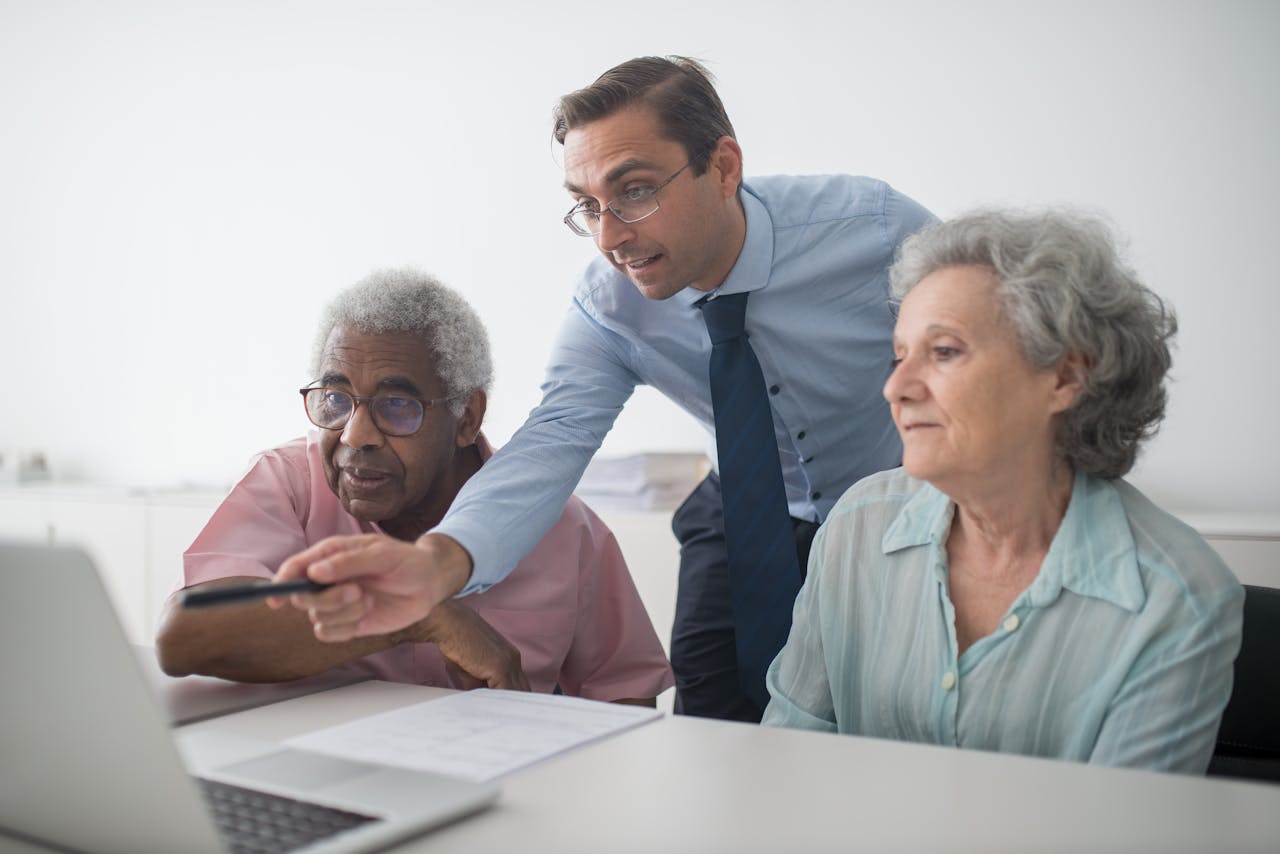 A business consultant explaining financial options to senior clients, using a laptop for illustration.