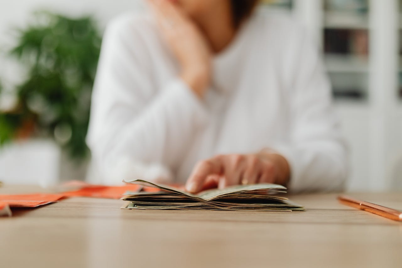 A woman sitting at a desk sorting through cash, focusing on household budgeting.